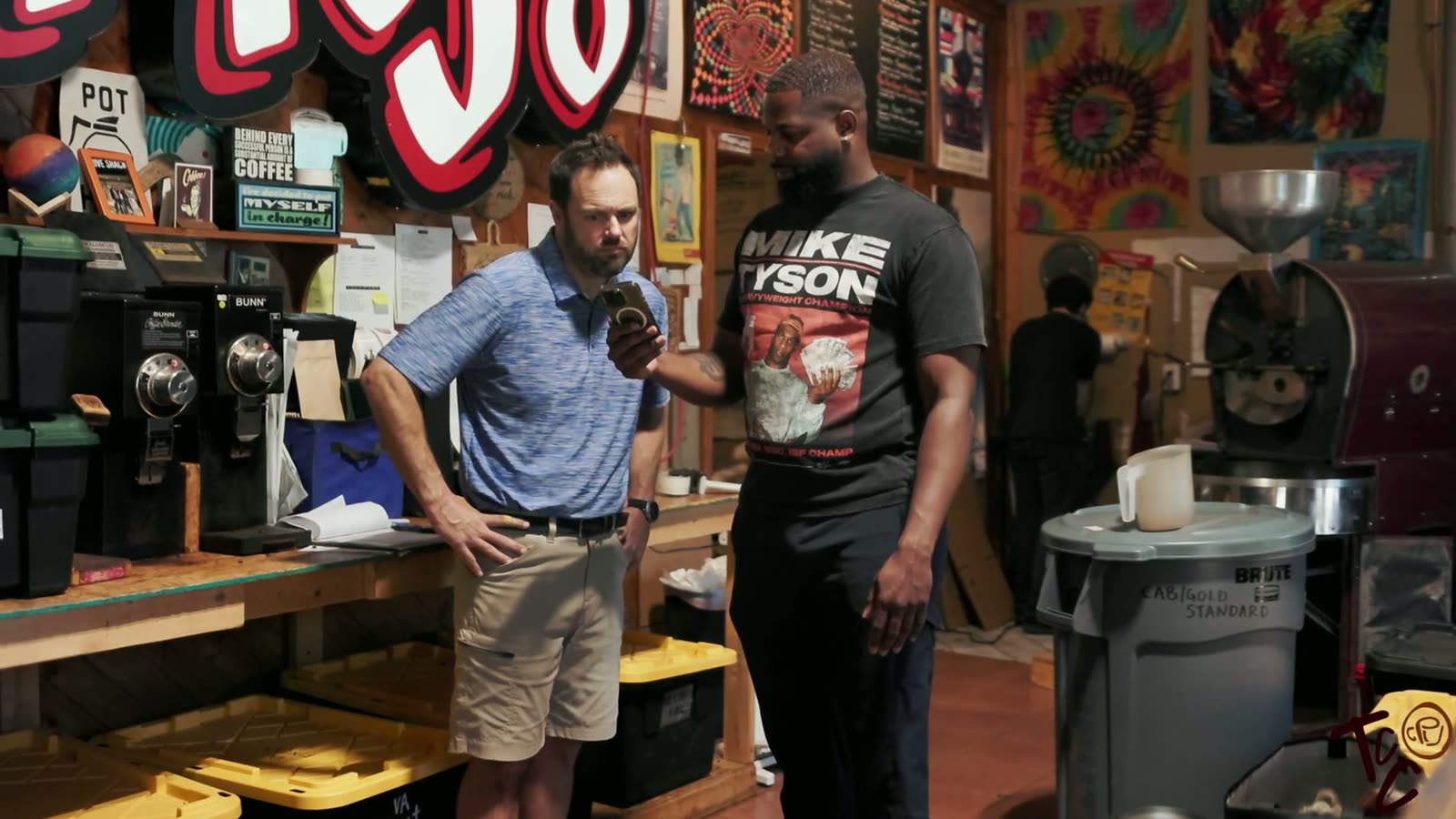 Two men talking in the roasting room surrounded by art